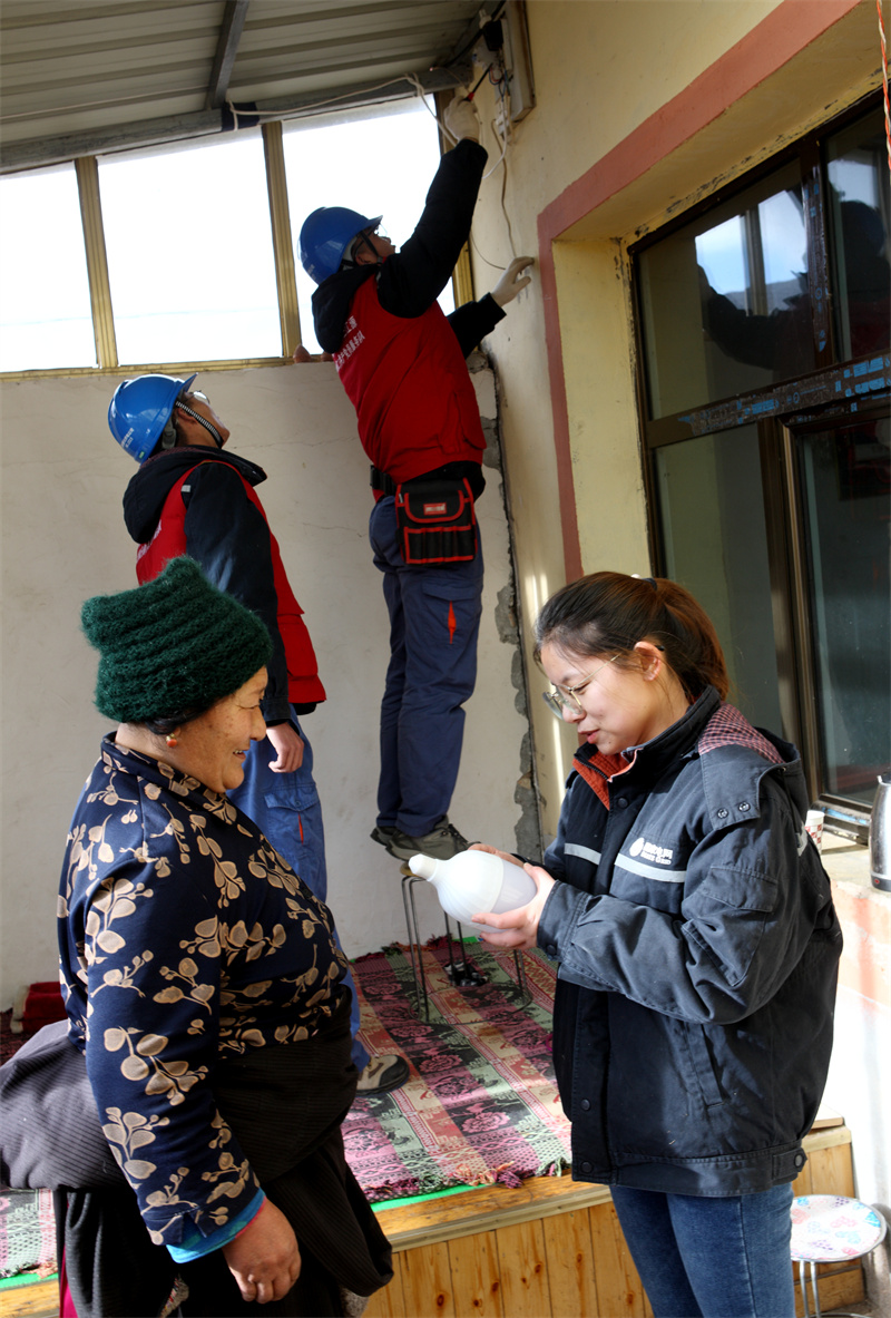 1月13日，國(guó)網(wǎng)青海同仁市供電公司員工為牧民群眾檢查用電線路并贈(zèng)送節(jié)能燈泡。祁正吉攝