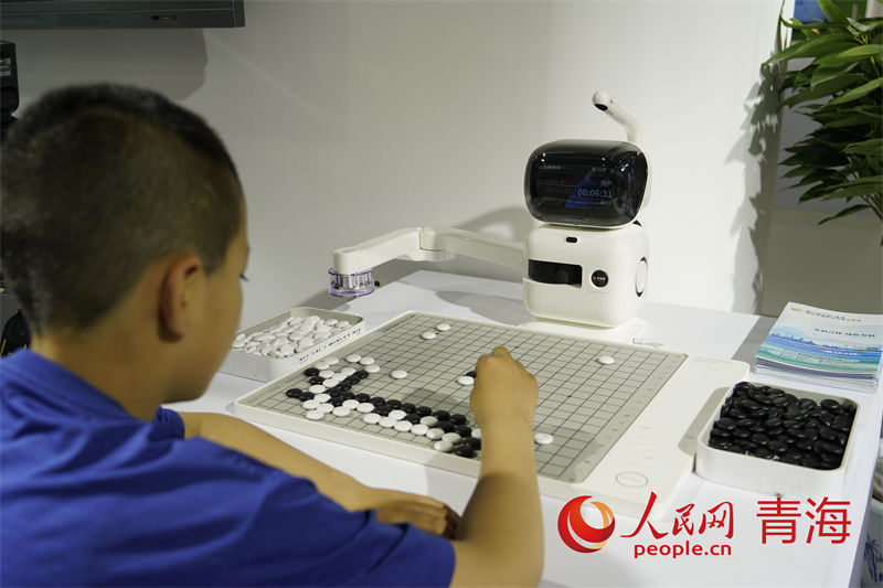綠色算力展館內(nèi)小朋友與機(jī)器人一起下棋。人民網(wǎng)記者 甘海瓊攝