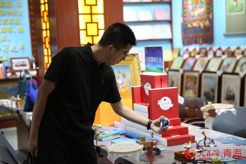 與會嘉賓了解海南州藏繡產(chǎn)品。人民網(wǎng) 馬可欣攝