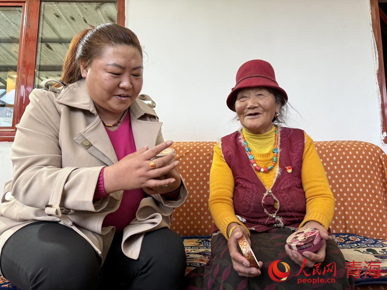 西毛（右）給索南吉展示在北京買到的紀(jì)念品。人民網(wǎng) 況玉攝